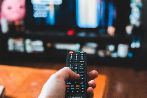 Man with remote control in hand watching tv.